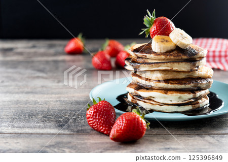 Pancakes with chocolate and fruit on wooden table Pancakes with chocolate and fruit on wooden table 125396849