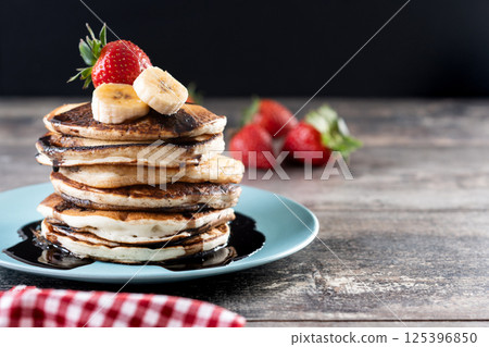 Pancakes with chocolate and fruit on wooden table 125396850