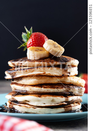 Pancakes with chocolate and fruit on wooden table Pancakes with chocolate and fruit on wooden table 125396851
