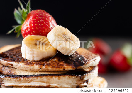 Pancakes with chocolate and fruit on wooden table 125396852