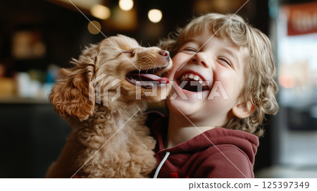 Little boy shares a joyful moment with his playful puppy in a warm indoor setting 125397349