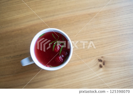 Raspberry tea in a white mug on a wooden table. 125398070