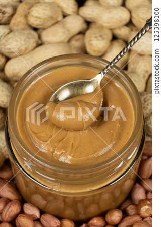 Peanut butter in a jar among scattered peanuts Peanut butter in a jar among scattered peanuts 125398100