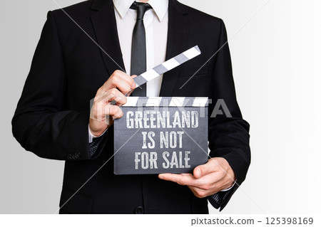 GREENLAND IS NOT FOR SALE. Businessman showing movie clapper GREENLAND IS NOT FOR SALE. Businessman showing movie clapper 125398169