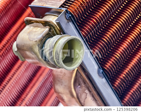 Close-up of industrial heat exchanger with copper fins and brass fittings in a factory setting during daytime Close-up of industrial heat exchanger with copper fins and brass fittings in a factory setting during daytime 125398206