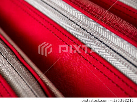 Detailed close-up view of textured patterns on fabric in shades of red and gray used for a travel accessory or luggage item 125398215