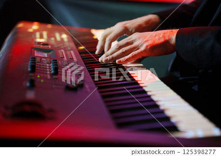 Men's hands play the keys of an electronic piano.  125398277