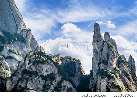 Rescue helicopter in the Montserrat massif, a mountain in the province of Barcelona, on a day with blue sky and white clouds Rescue helicopter in the Montserrat massif, a mountain in the province of Barcelona, on a day with blue sky and white clouds 125398305
