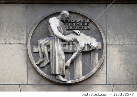 Herophilos, the first dissection. Stone relief at the building of the Faculte de Medicine Paris, France. 125398577