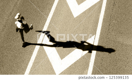 lone runner with dramatic elongated shadow cast 125399135