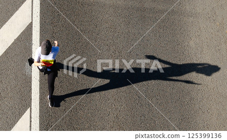 Aerial view of marathon runner using her smartphone on urban road 125399136