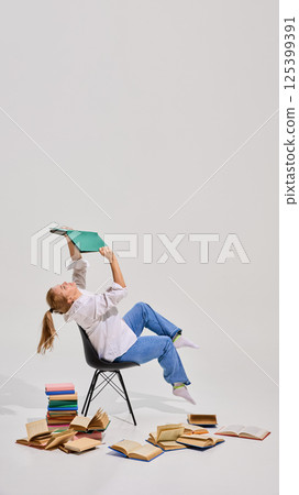 Senior woman leaning on chair and reading book surrounded by many books against white background. Exams preparation. 125399391