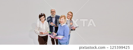 Positive elderly people, man and woman standing with books and notes against white background. representing special educational courses for seniors. Positive elderly people, man and woman standing with books and notes against white background. representing special educational courses for seniors. 125399425