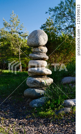 Zen garden meditation space with carefully balanced stone cairn, natural rock formations, lush green grass Zen garden meditation space with carefully balanced stone cairn, natural rock formations, lush green grass 125399613