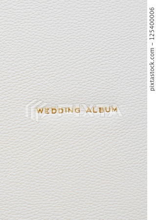 The inscription Wedding Album in gold letters on the white leather cover of book 125400006