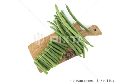 Fresh green beans and chopped green beans lying on wooden cutting board 125401105