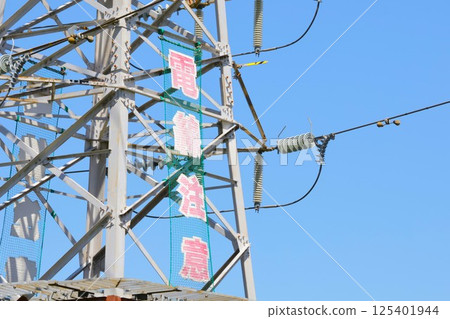一座帶有電線的塔，旁邊還有一塊警示牌，上面寫著“小心電線” 125401944
