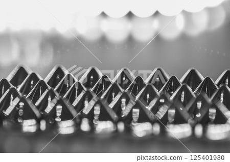 Close-up macro of sewing studs arranged in symmetrical rows in black and white abstraction Close-up macro of sewing studs arranged in symmetrical rows in black and white abstraction 125401980