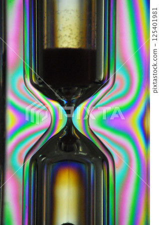 A colorful rainbow hourglass measuring time against a black background 125401981