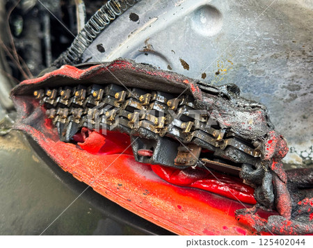 Close-up of a severely burned LED tail light module from a car, showing melted plastic housing, exposed electrical components, and heat-damaged internal structure 125402044