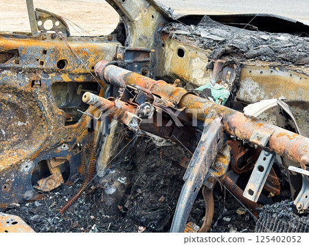 Burned steering column and dashboard frame from a car showing rusted metal structure, melted components, and complete fire destruction of the interior Burned steering column and dashboard frame from a car showing rusted metal structure, melted components, and complete fire destruction of the interior 125402052