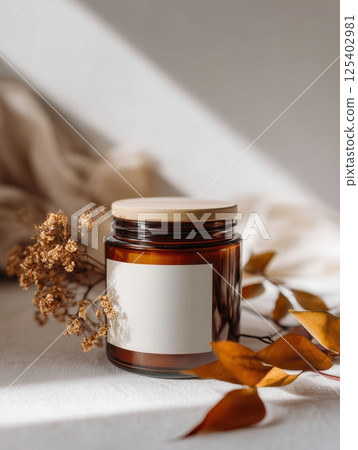 Amber jar candle mockup decorated with flowers and plants, creative design preview template for candle branding, organic scented candle with decor 125402981