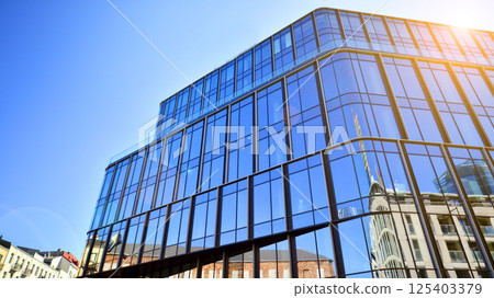 Modern office building with glass facade on a clear sky background. Transparent glass wall of office building. 125403379