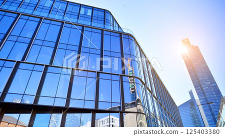Modern office building with glass facade on a clear sky background. Transparent glass wall of office building. 125403380