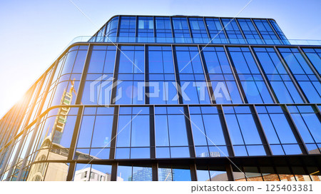 Modern office building with glass facade on a clear sky background. Transparent glass wall of office building. 125403381