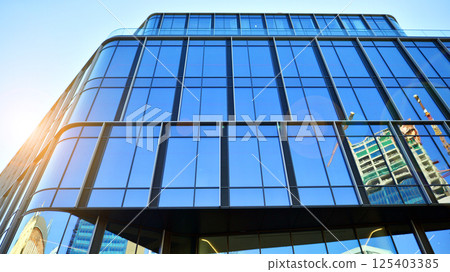 Modern office building with glass facade on a clear sky background. Transparent glass wall of office building. 125403385