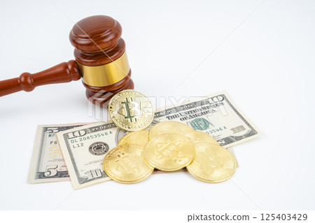 Judge gavel and bitcoins with USD banknotes on white. 125403429