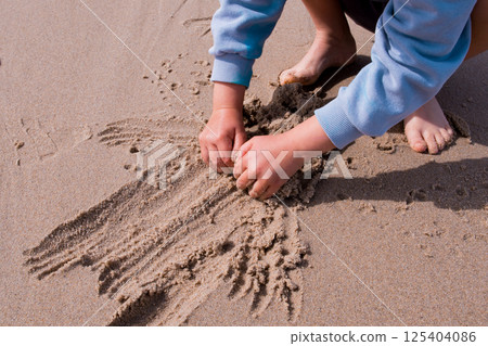 Child playing in sand at beach with hands and feet visible Child playing in sand at beach with hands and feet visible 125404086