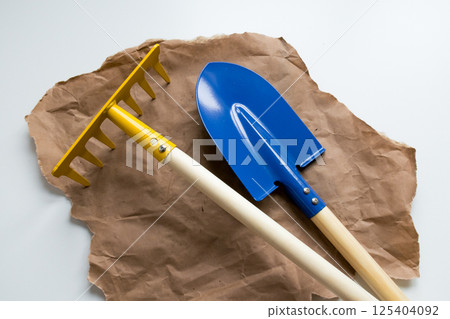 Yellow rake and blue shovel on brown paper for gardening and landscaping 125404092