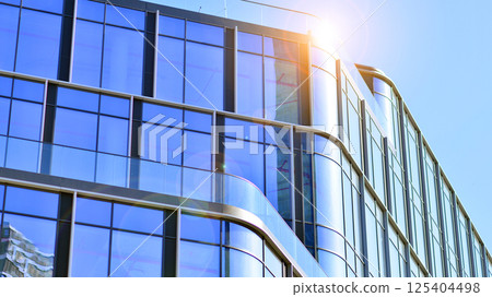 Downtown corporate business district architecture. Glass reflective office buildings against blue sky and sun light. Economy, finances, business activity concept. Rising sun on the horizon. 125404498