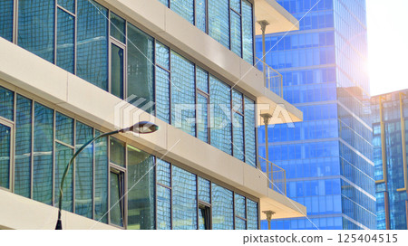 Downtown corporate business district architecture. Glass reflective office buildings against blue sky and sun light. Economy, finances, business activity concept. Rising sun on the horizon. 125404515