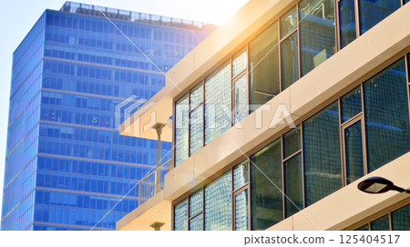 Downtown corporate business district architecture. Glass reflective office buildings against blue sky and sun light. Economy, finances, business activity concept. Rising sun on the horizon. Downtown corporate business district architecture. Glass reflective office buildings against blue sky and sun light. Economy, finances, business activity concept. Rising sun on the horizon. 125404517