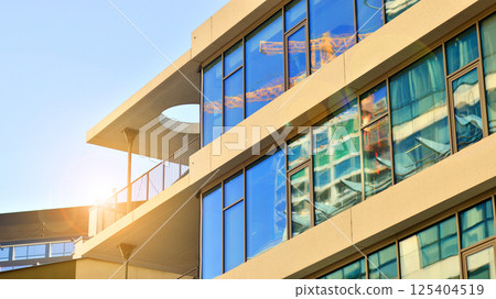 Downtown corporate business district architecture. Glass reflective office buildings against blue sky and sun light. Economy, finances, business activity concept. Rising sun on the horizon. 125404519