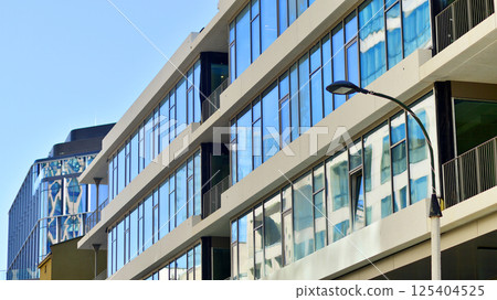 Downtown corporate business district architecture. Glass reflective office buildings against blue sky and sun light. Economy, finances, business activity concept. Rising sun on the horizon. Downtown corporate business district architecture. Glass reflective office buildings against blue sky and sun light. Economy, finances, business activity concept. Rising sun on the horizon. 125404525