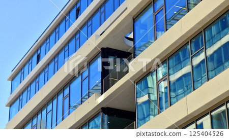 Downtown corporate business district architecture. Glass reflective office buildings against blue sky and sun light. Economy, finances, business activity concept. Rising sun on the horizon. 125404526