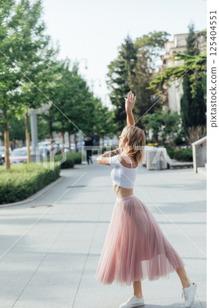 Blonde in dress dancing to music on street Blonde in dress dancing to music on street 125404551