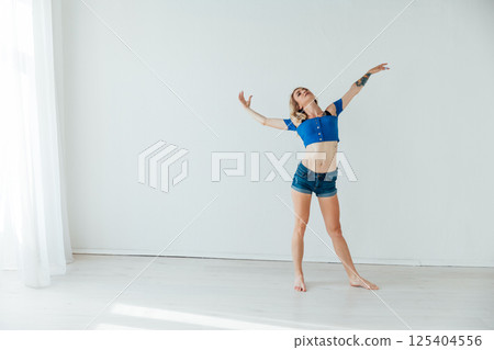 Blonde dancing to music alone in a room with a window Blonde dancing to music alone in a room with a window 125404556