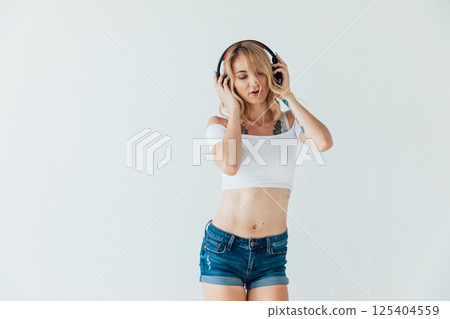 Blonde woman listening to music in headphones and dancing 125404559