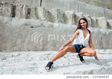 brunette woman in short shorts on the rocks in summer brunette woman in short shorts on the rocks in summer 125404597