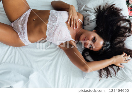 woman in light lingerie lying in the bedroom on the bed in the evening woman in light lingerie lying in the bedroom on the bed in the evening 125404600