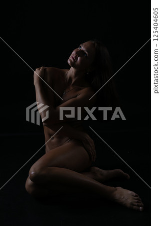 Brunette with a body sitting alone in the dark 125404605