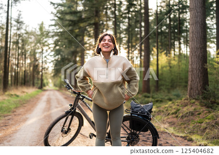 Pedal Powered Peace. Woman explores woodland paths with a smile, merging calm, cardio and nature's reset 125404682