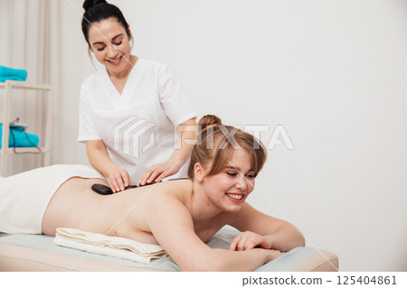 Woman on table at masseur on back massage in spa Woman on table at masseur on back massage in spa 125404861