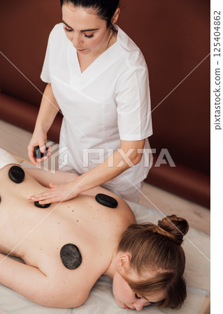 Woman on table at masseur on back massage in spa Woman on table at masseur on back massage in spa 125404862