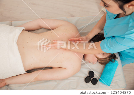 Woman on table at masseur on back massage Woman on table at masseur on back massage 125404870