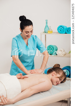 Woman massage therapist doing relaxing medical back massage in spa Woman massage therapist doing relaxing medical back massage in spa 125404875